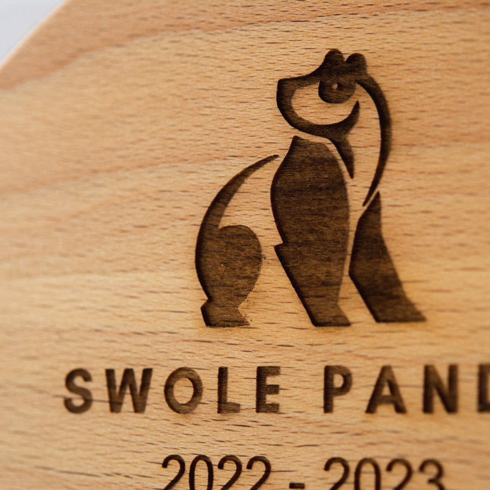 Wooden plaque with 'Swole Panda' logo and text on a wooden background