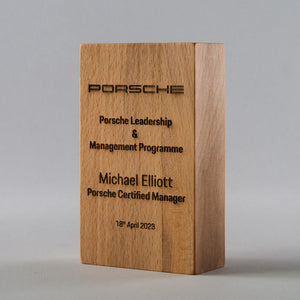 Wooden plaque with Porsche branding and engraved text on a gray background