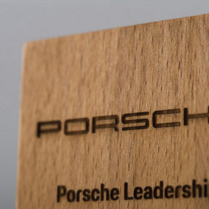 Wooden block award with Porsche branding on a gray background