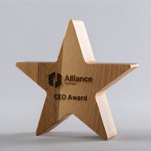 Wooden star-shaped award with 'Alliance homes' logo on a gray background